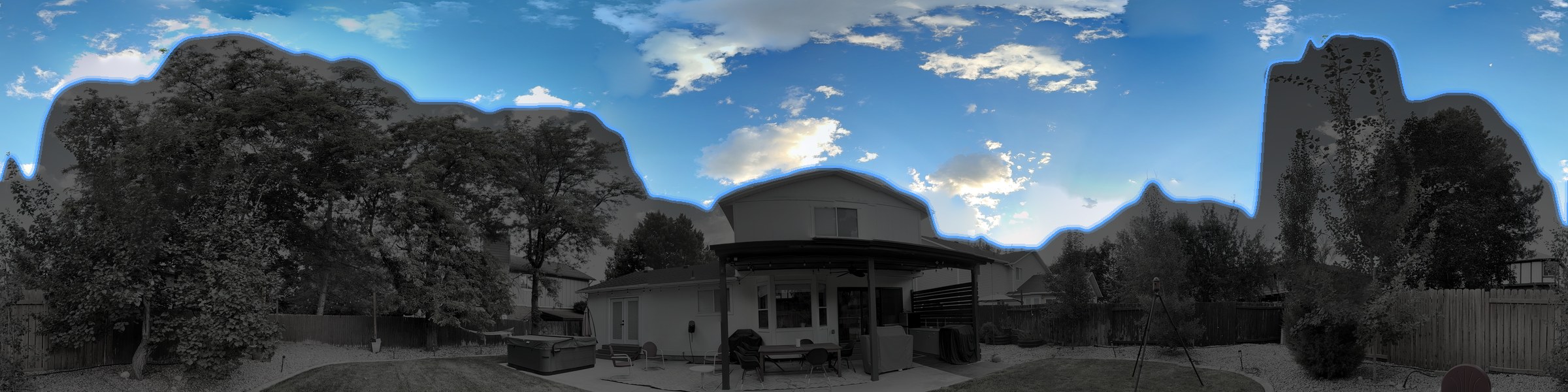 The same skyline as ARIS sees it — sky vivid, every obstruction darkened, the segmentation boundary traced in blue up and around each tree, twig, and roofline