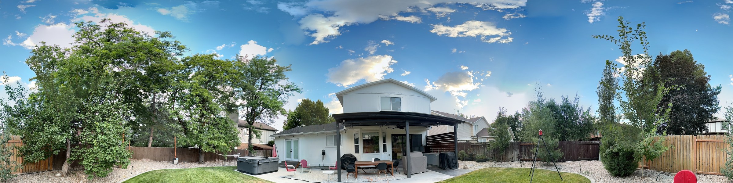 Raw stitched skyline band — a real backyard panorama, bright clouds over the trees and rooflines